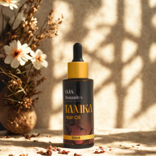 Bottle of Tanika Hair Oil by OJA Botanics with golden cap and herbal backdrop.