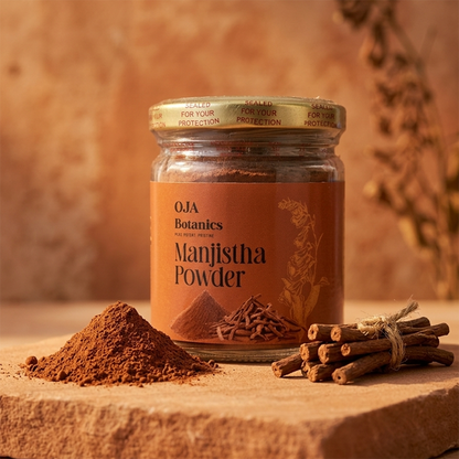 Jar of OJA Botanics Manjistha Powder with cinnamon sticks and powder on a wooden surface