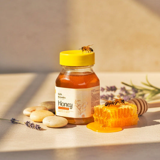 Jar of honey with a bee on top, surrounded by honeycomb and lavender flowers on a wooden surface.